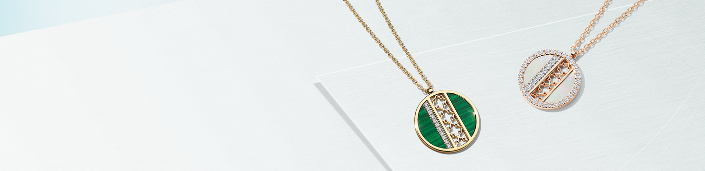 Birks malachite and mother-of-pearl pendants on a light blue background.